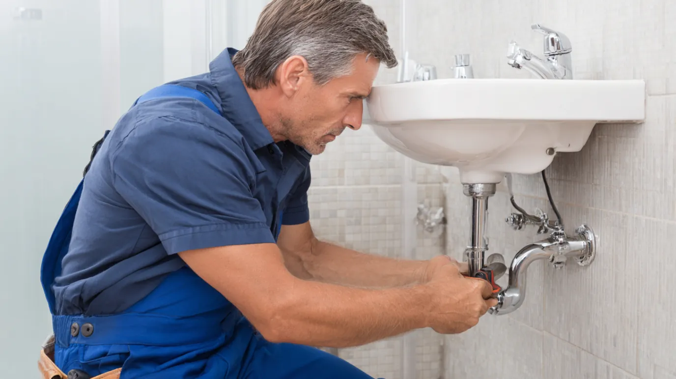 Rooter service technician using drain cable to clear sewer clog in Torrance